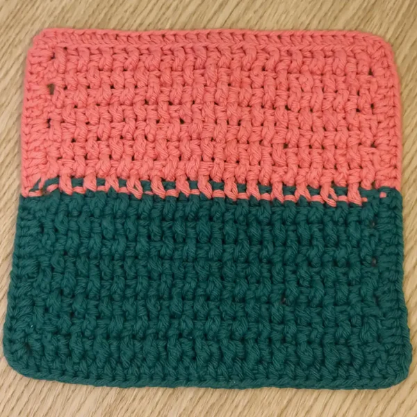 Hand-crocheted two-tone washcloth in Tangerine and Forest Green by Patient Calf, featuring a textured cotton stitch pattern.