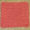 Solid Tangerine orange hand-crocheted cotton washcloth showing neat, compact stitch texture.