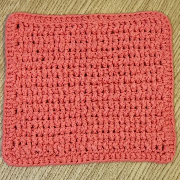 Solid Tangerine orange hand-crocheted cotton washcloth showing neat, compact stitch texture.