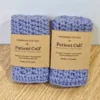 A stacked set of two handmade periwinkle blue cotton washcloths by Patient Calf, featuring brown paper branding bands and "Made in Canada" labels.
