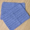 Two overlapping handmade periwinkle cotton washcloths showing the soft, breathable crochet texture and handmade quality.