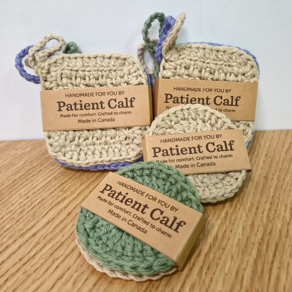 A mixed set of 6 handmade cotton face scrubbies by Patient Calf, featuring 4 square scrubbies with hanging loops and 2 round crochet discs in earthy sand, sage green, and periwinkle-lilac tones.