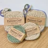 Close-up of Patient Calf handmade cotton scrubbies in square and round shapes, packaged with "Handmade For You" and "Made in Canada" brown paper bands.