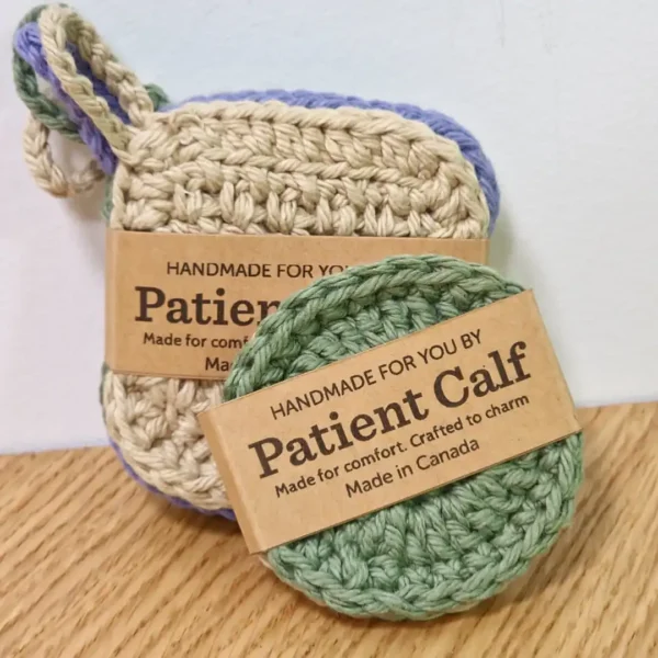 sand-colored square scrubby with a hanging loop and sage green round crochet face disc , both featuring Patient Calf branding and "Made in Canada" labels.