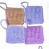 A collection of four Iris scrubbies by Patient Calf in Fudge, Soft Lilac, and Vintage Purple, showing the solid color range.