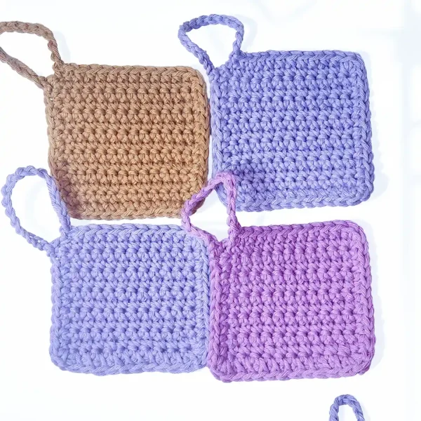 A collection of four Iris scrubbies by Patient Calf in Fudge, Soft Lilac, and Vintage Purple, showing the solid color range.