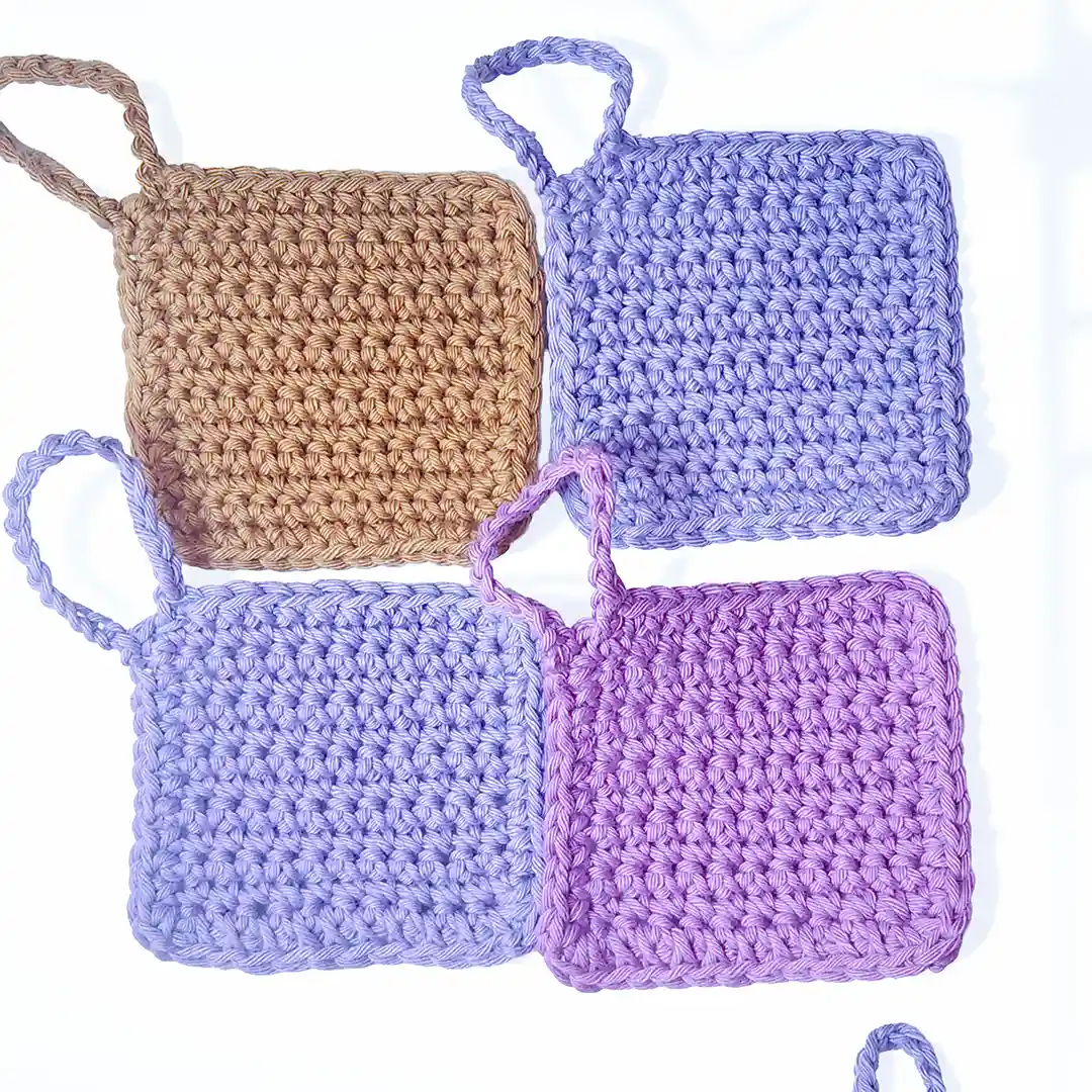 A collection of four Iris scrubbies by Patient Calf in Fudge, Soft Lilac, and Vintage Purple, showing the solid color range.