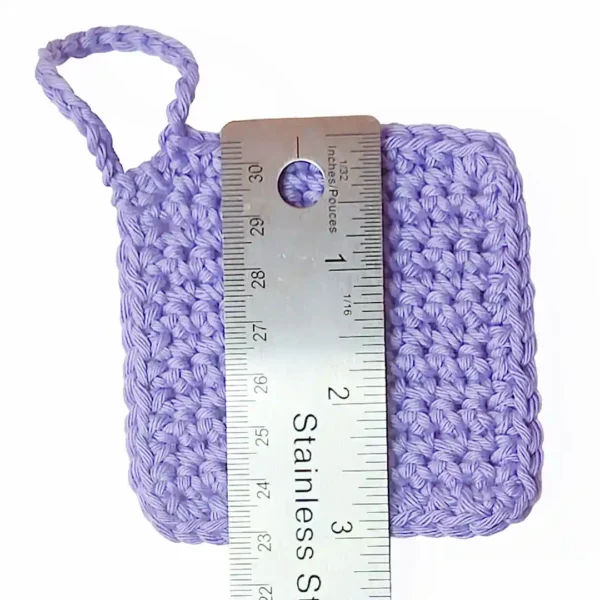 A soft lilac Iris scrubbie by Patient Calf shown with a ruler measuring 3 inches (7.6 cm) in height.