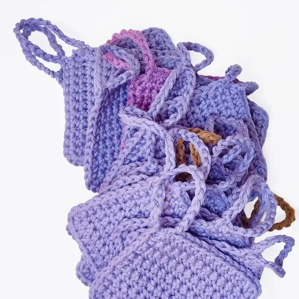 A textured stack of hand-crocheted Iris scrubbies in Soft Lilac and Fudge brown showing the finger loops.